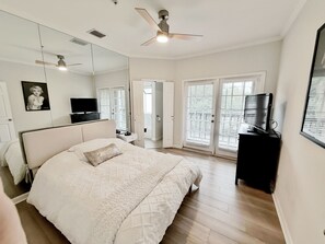 A bedroom with a bed, a television, a ceiling fan, and a large window with blinds. - 1BR Condo Near Love Field and Medical District - Pool and Gated Parking (Dallas)