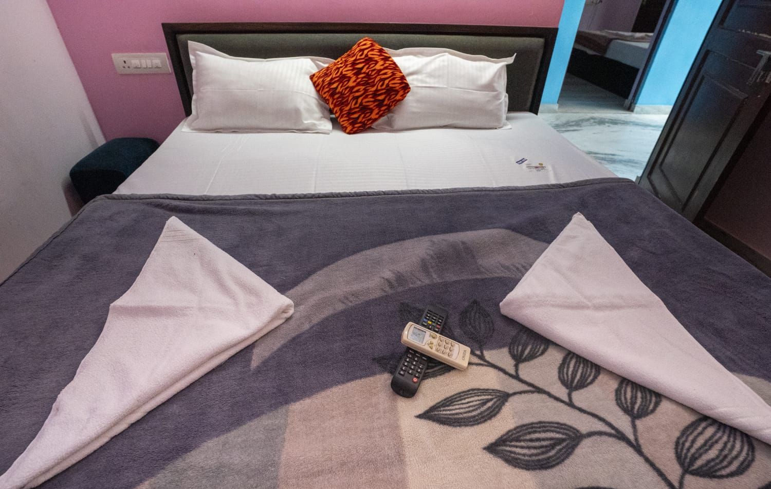 Una cama bien hecha con almohadas, una colcha y un control remoto.