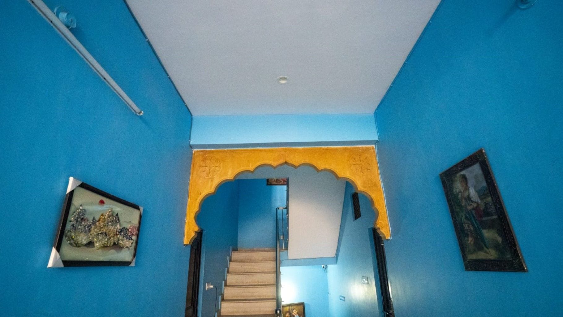 A hallway with blue walls, a wooden staircase, and a decorative archway.