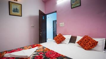 A hotel room with a bed, pillows, a wall-mounted light, and a door leading to another room.