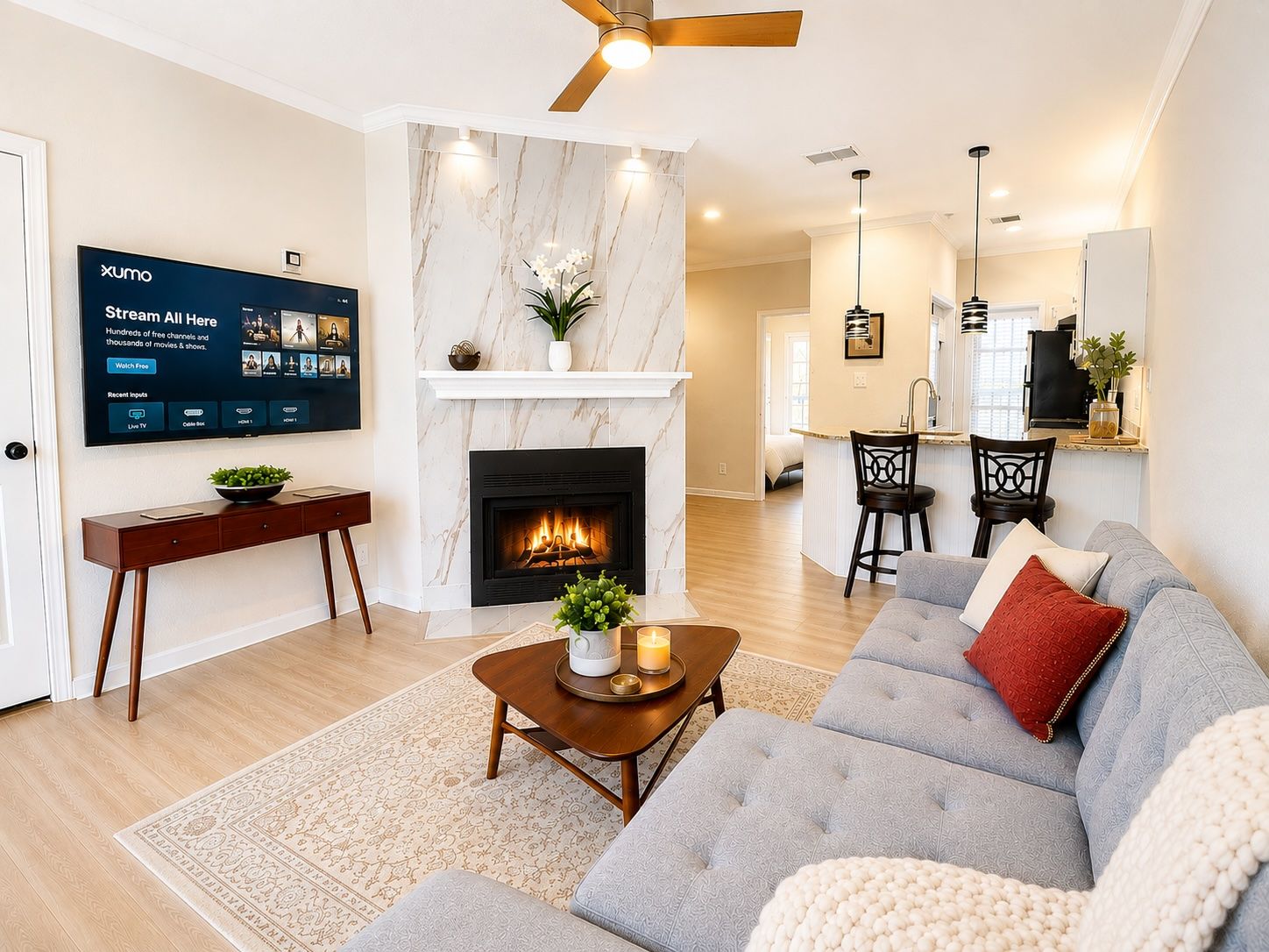 A modern living room with a fireplace, a flat-screen TV, and a dining area.