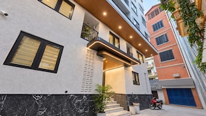 Un edificio moderno con una escalera que conduce a un balcón, una motocicleta roja estacionada afuera y una cámara de seguridad en la pared.
