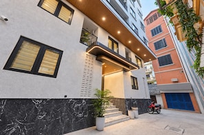 Un edificio moderno con una escalera que conduce a un balcón, una motocicleta roja estacionada afuera y una cámara de seguridad en la pared.