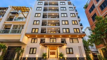 A multi-story hotel with a modern facade, balconies, and a well-lit entrance.