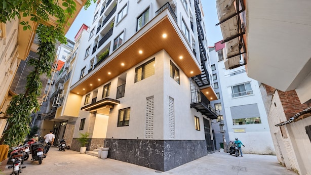 Un edificio residencial de varios pisos con un diseño moderno, que incluye un balcón con barandillas de madera y un techo plano.