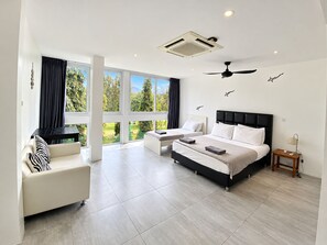 A modern hotel room with a large bed, a sofa, and a view of greenery through large windows. - 5 BDRM & BATHROOM Pool Villa. Golf Views, 7kms to Patong. Peaceful & private (Tambon Kathu)