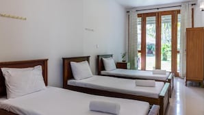 Habitación de hotel con dos camas individuales, un armario de madera y un ventanal corredero que da a un balcón.