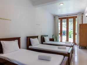 Ein Hotelzimmer mit zwei Einzelbetten, einem Holzschrank und einer Glastür, die auf einen Balkon führt.