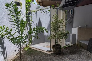 Zona exterior petita amb una banca de formigó, una planta en test i una porta que dona a un espai cobert.