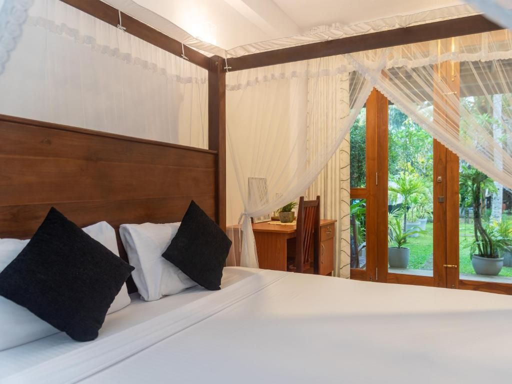 Un dormitorio con una cama grande, un cabecero de madera y vistas a un jardín a través de un ventanal.