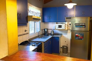 Une cuisine de taille réduite équipée d’une cuisinière à gaz, d’un four à micro-ondes et d’un réfrigérateur.