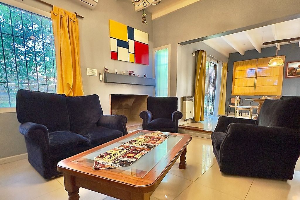 Un salon avec une cheminée, deux canapés, une table basse et un tableau abstrait aux couleurs vives accroché au mur.