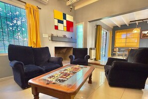 Un salon avec une cheminée, deux canapés, une table basse et un tableau abstrait aux couleurs vives accroché au mur.