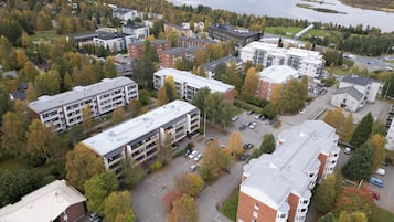 An aerial view of a residential area with multiple buildings, a parking lot, and a river in the background.