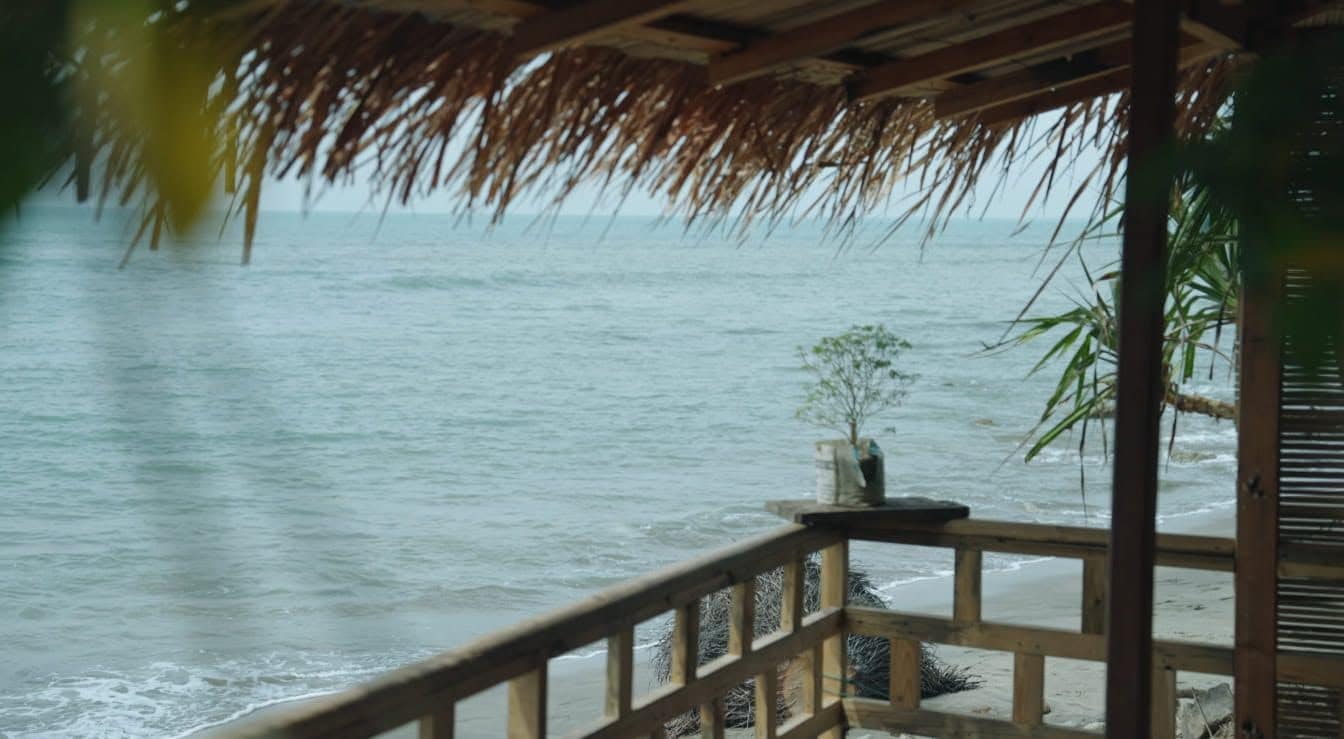 Una terraza de madera con barandilla que da a una playa.