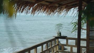 Una terraza de madera con barandilla que da a una playa.