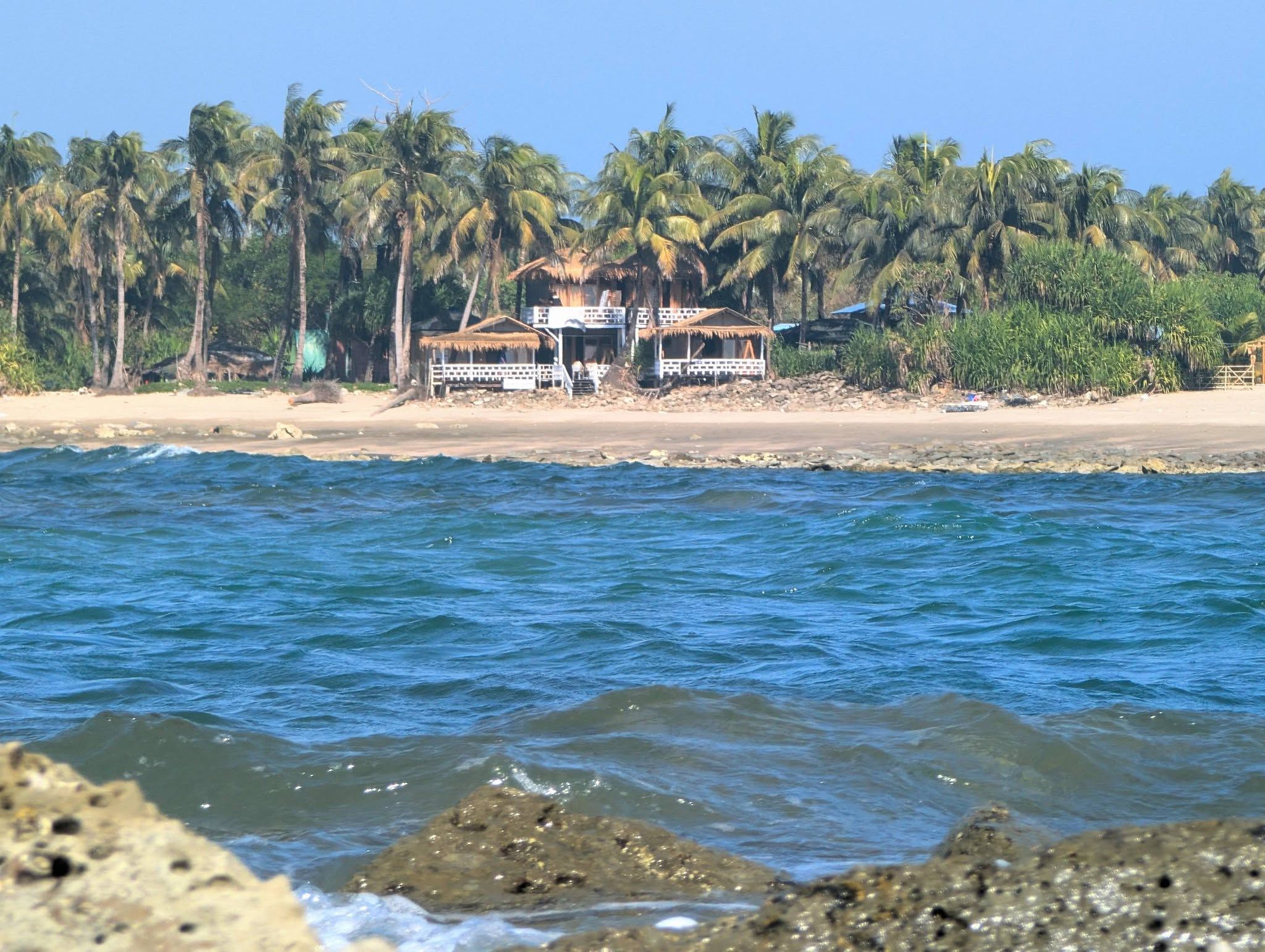 Une propriété située en bord de mer, dotée d’une structure à toit de chaume, de palmiers et d’une plage de sable.