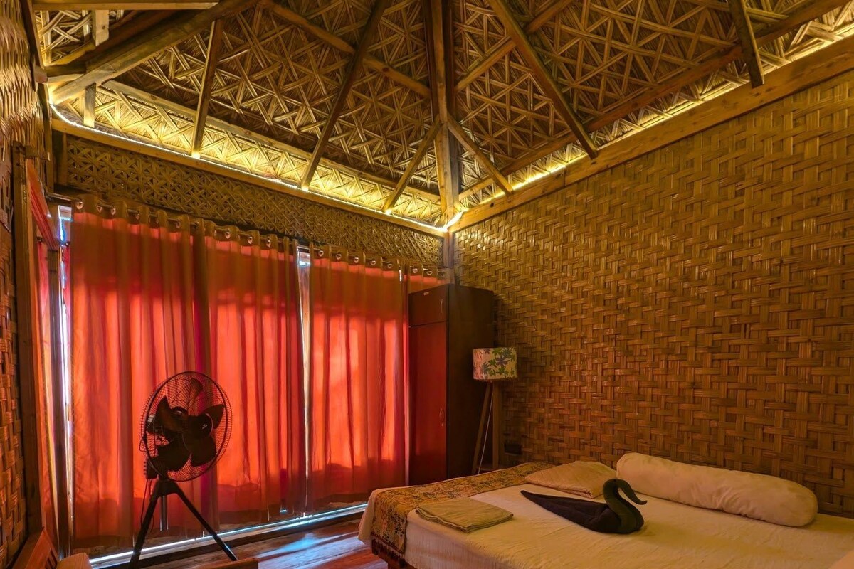 A room with a bed, a desk, a chair, a lamp, and a window with curtains.