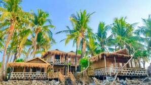A beachfront bungalow with a thatched roof, surrounded by palm trees. - Sailor Eco Resort. Saint Martin (Chittagong Division)
