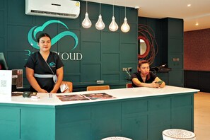 Ein Empfangsschalter mit einer türkisfarbenen Theke, ein Logo mit stilisierter Wolke und Welle, und ein Schild mit der Aufschrift 'CLOUD'.