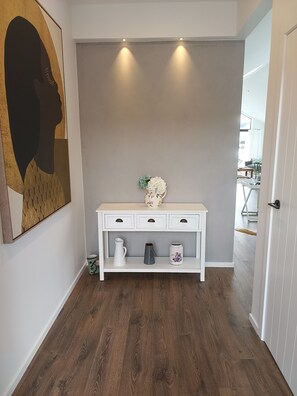 A hallway with a white console table, a decorative vase, and a painting on the wall. - Cromwell Central Charm. Perfect location to explore the stunning Central Otago. (Cromwell)