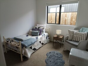 A bedroom with a bed, a chair, a small table, and a window. - Cromwell Central Charm. Perfect location to explore the stunning Central Otago. (Cromwell)