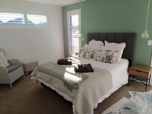 A bedroom with a bed, a chair, a bedside table, and a window. - Cromwell Central Charm. Perfect location to explore the stunning Central Otago. (Cromwell)