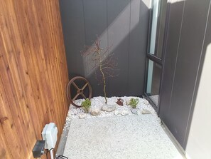 A small garden area with a wooden fence, a metal wheel, and a potted plant. - Cromwell Central Charm. Perfect location to explore the stunning Central Otago. (Cromwell)