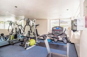 A gym with exercise equipment, a treadmill, and a mirrored wall. - Cozy 1-bedroom apartment in lovely Los Angeles with AC and gym access (Los Angeles)