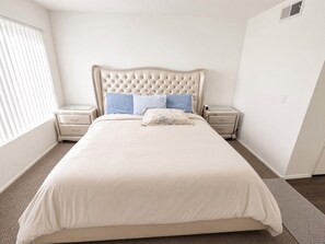 A bedroom with a large bed, two bedside tables, and a window with blinds. - Cozy 1-bedroom apartment in lovely Los Angeles with AC and gym access (Los Angeles)