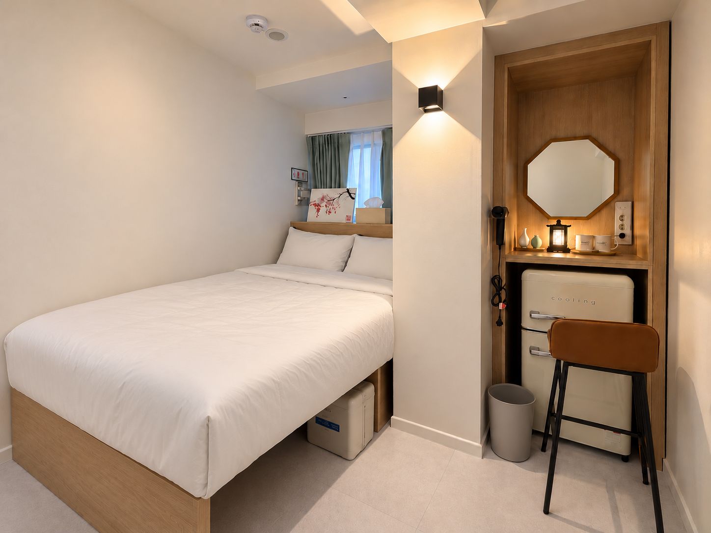 A hotel room with a bed, a desk, a mirror, and a small cabinet.