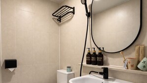 A modern bathroom with a toilet, sink, and mirror. - Hub82 (Seoul)