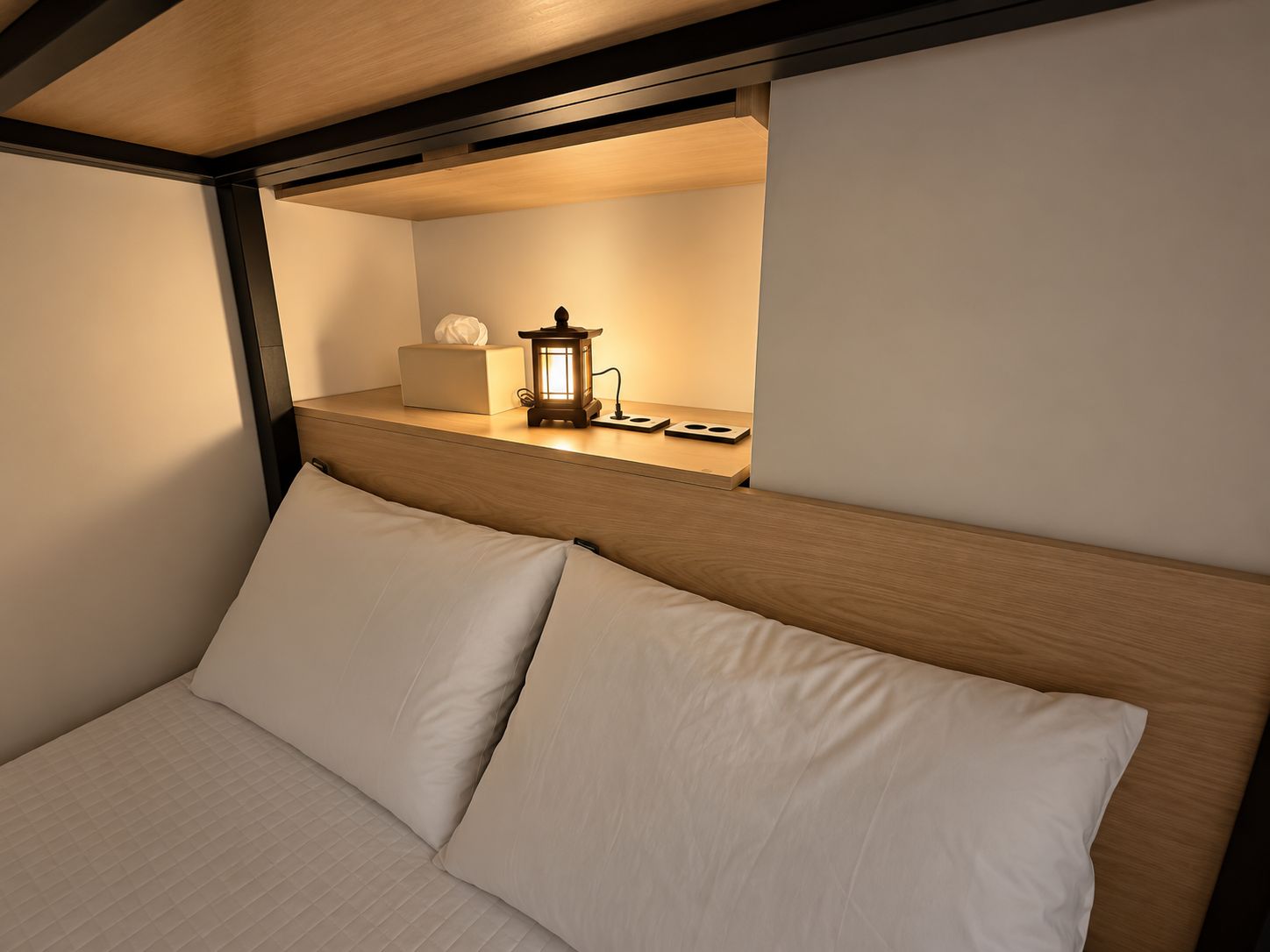 Un lit avec une tête de lit, une table de chevet avec une lampe et une étagère murale avec une lanterne.