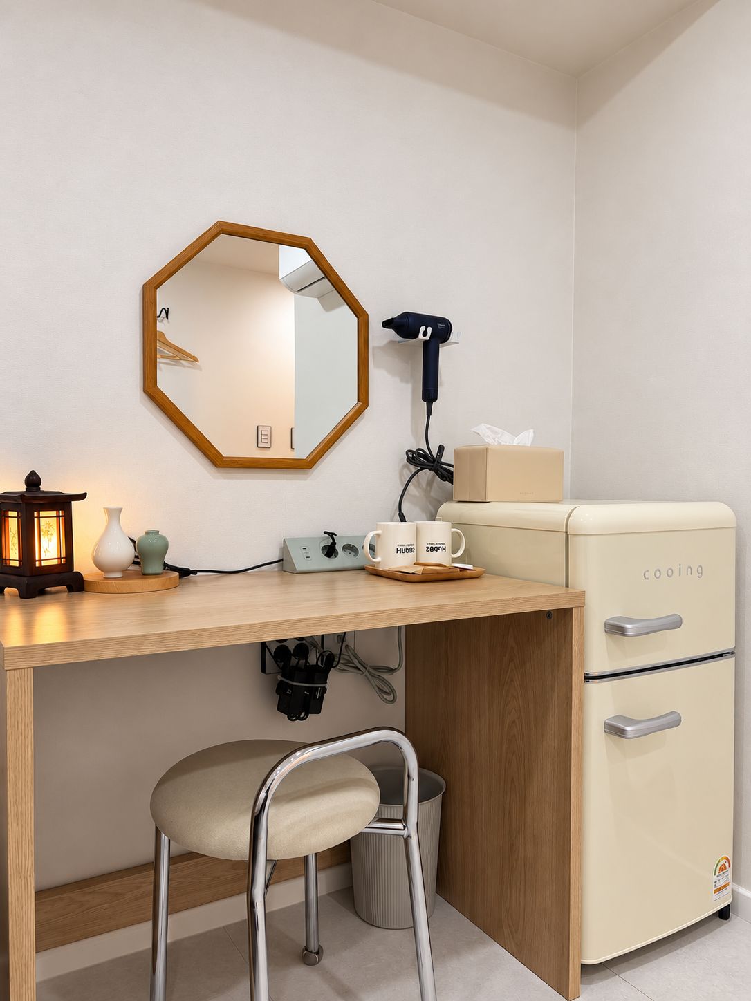 Una kitchenette compacta con cubierta de madera, un refrigerador blanco, un secador de pelo y un espejo.