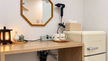 Una kitchenette compacta con cubierta de madera, un refrigerador blanco, un secador de pelo y un espejo.