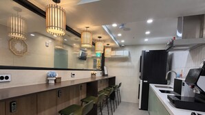 A modern kitchen with a bar area, equipped with a coffee machine, a sink, and a refrigerator. - Hub82 (Seoul)