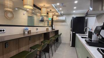 Cocina moderna con barra, equipada con cafetera, lavamanos y refrigerador.