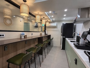 Une cuisine moderne dotée d’un coin bar, équipée d’une machine à café, d’un  évier et d’un réfrigérateur.