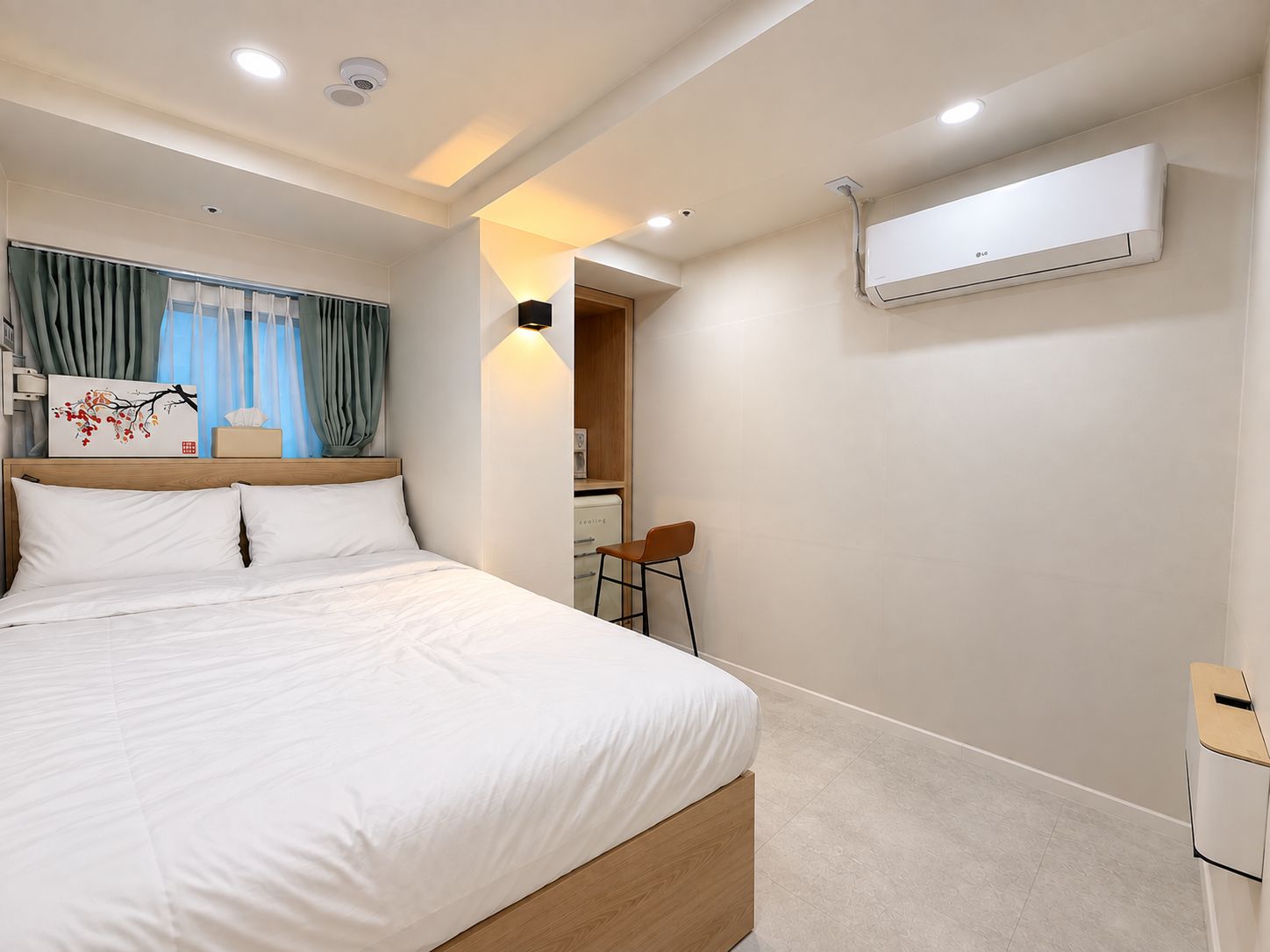 Habitación de hotel con cama, escritorio, aire acondicionado y vista a un pasillo.