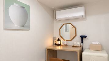 Una habitación moderna con escritorio, una silla, un refrigerador pequeño, un espejo y un aire acondicionado de pared.