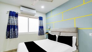 Een hotelkamer met een bed, gordijnen, een airconditioning en een muur met geometrische patronen.