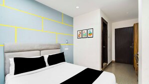 Een hotelkamer met een bed, een muur met geometrische patronen en een deur.