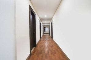 A long, narrow hallway with wooden flooring and white walls, leading to multiple doors. - Townhouse Oak Shilparamam Art (Hyderabad)