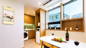 Una cocina moderna con comedor, una ventana que ofrece vistas a un edificio y una botella de vino sobre la mesa.