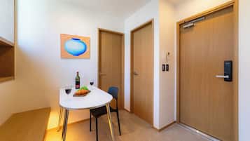 Habitación de hotel con zona de comedor, un cuadro en la pared y una puerta con cerradura.