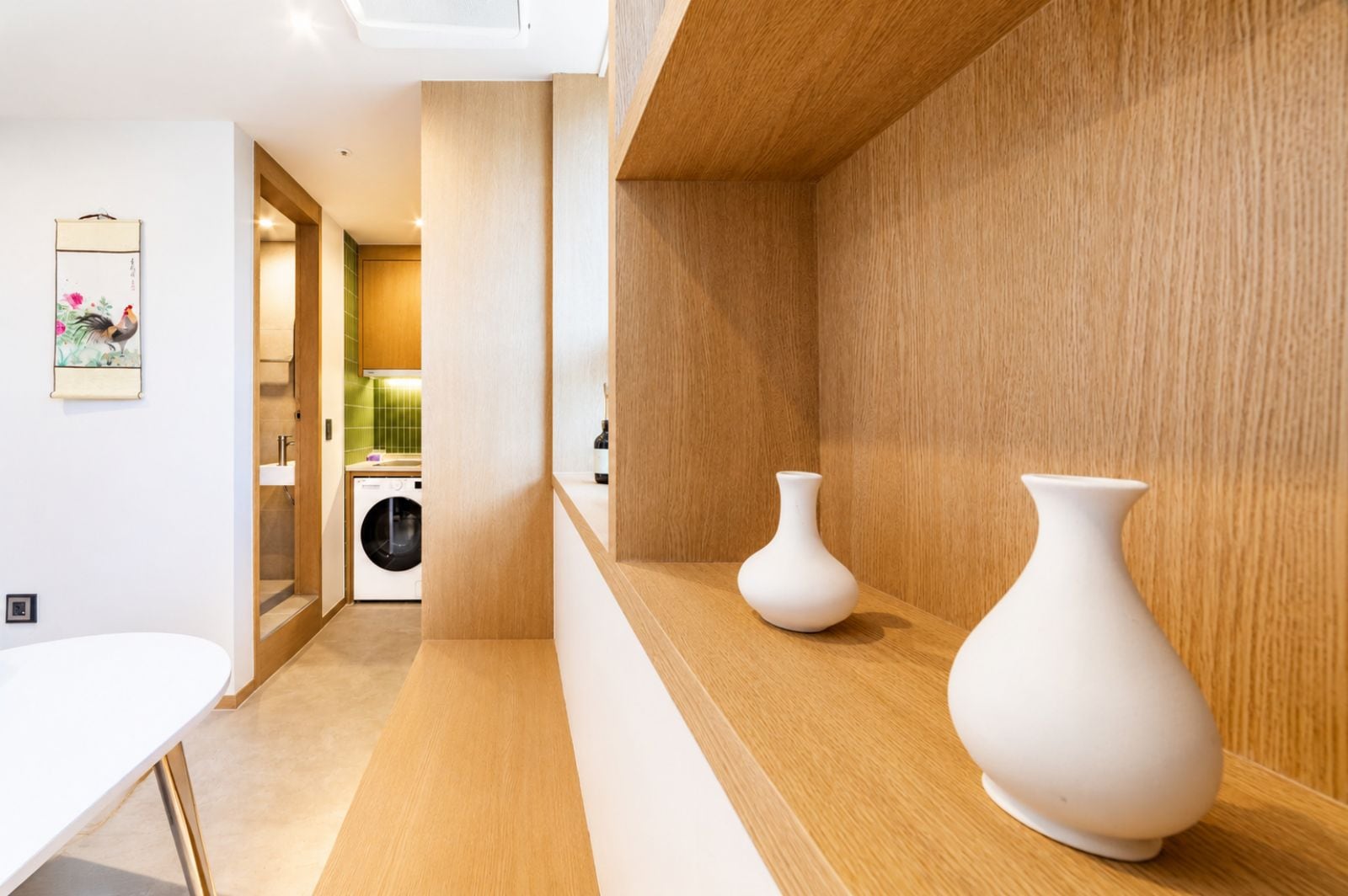Una cocina moderna con lavadora, armarios de madera y dos jarrones blancos sobre la encimera.