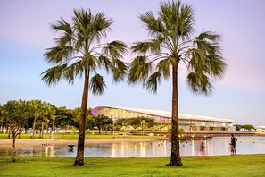 A park with palm trees and a modern building in the background. - Studio In Darwin City Centre With Rooftop Deck (Darwin)