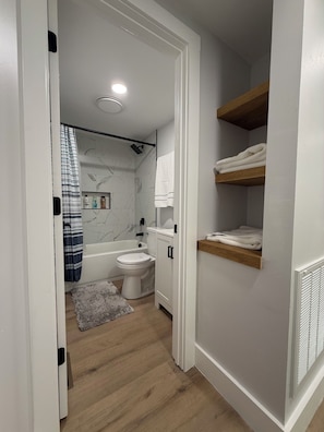 Un baño moderno con bañera, inodoro y zona de ducha.