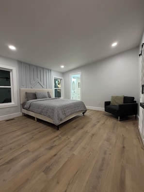 A bedroom with a bed, a chair, and a window.