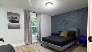 Ein modernes Schlafzimmer mit einem Bett, einem Schreibtisch und einem Fenster mit Vorhängen.